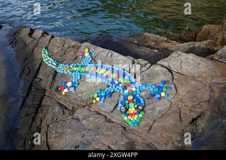 Gecko-Design auf Küstenfelsen aus Flaschenaufsätzen und Zigarettenanzündern, die an Stränden in Milina, South Pelion, Griechenland gesammelt wurden Stockfoto