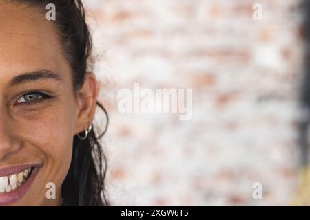 Die junge birassische Frau lächelt sanft, mit Kopierraum. Ihre hellen Augen und ihr warmer Ausdruck rufen ein Gefühl der Freundlichkeit und Zugänglichkeit hervor, unverfälscht. Stockfoto