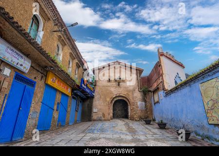 Chefchaouen, Marokko - 25. März 2024: Ein rustikaler Bogengang zur Altstadt mit markanten blau lackierten Wänden und Terrakottadächern. Stockfoto