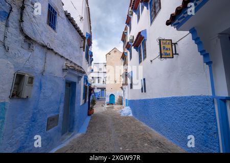 Ein altes Hotelschild hängt an der Wand der engen Gasse. Marokko. Die Häuser in Blau- und Weißtönen sind traumhaft und charmant. Chefchaouen. Stockfoto