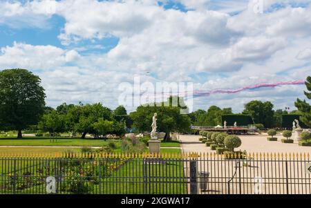 Paris, Frankreich. Juli 2024. Die Statuen des Jardin des Tuileries bleiben unbeeindruckt, da die Alpha Jets der Patrouille de France vor dem Bastille Day blaue, weiße und rote Rauchspuren abgeben, die die französische Nationalflagge darstellen Stockfoto