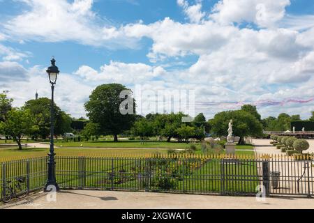 Eine Vintage-Lampe im Jardin des Tuileries bleibt unbeeindruckt, da die Alpha Jets der Patrouille de France vor dem Bastille Day blaue, weiße und rote Rauchspuren abgeben, die die französische Nationalflagge darstellen Stockfoto