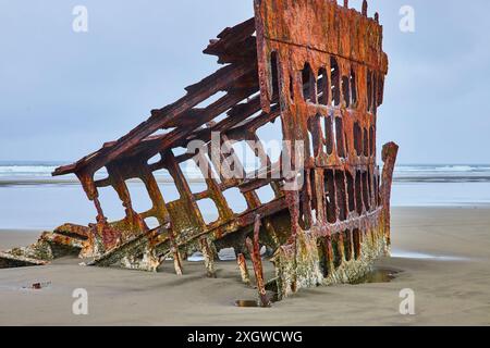 Verrostetes Schiffswrack am Sandstrand vor dem Hintergrund des Ozeans - Perspektive auf Augenhöhe Stockfoto