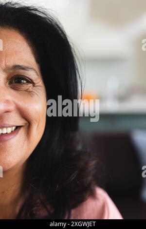 Vertikales Halbporträt einer glücklichen älteren birassischen Frau mit schwarzen Haaren, die zu Hause lächelt, Kopierraum. Wohlbefinden, häusliches Leben und Seniorenleben, unal Stockfoto