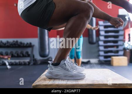 Ein fitter Afroamerikaner führt im Fitnessstudio einen Boxsprung durch. Sein explosives Krafttraining zeigt intensive Trainingsroutinen. Stockfoto
