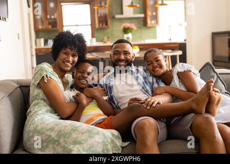 Vielfältige Familie genießt eine angenehme Zeit zu Hause. Sie teilen sich einen warmen, bequemen Moment auf der Couch und strahlen Glück und Einheit aus. Stockfoto