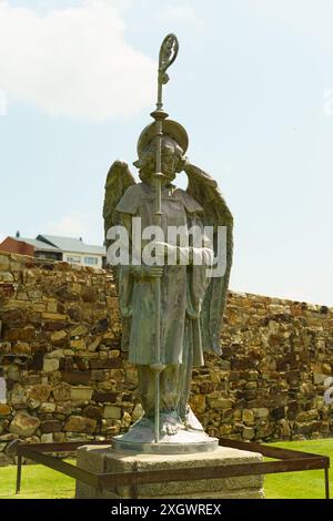 Astorga, Spanien – 4. Juni 2023: Eine Bronzeskulptur eines Engels, der einen Crosier hält und in den Himmel blickt, steht an einer Steinmauer am Episco Stockfoto