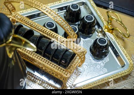 Schwarzer Hochglanzkaffee auf metallischem und goldenem Tablett für Feiertage und Familientreffen Stockfoto