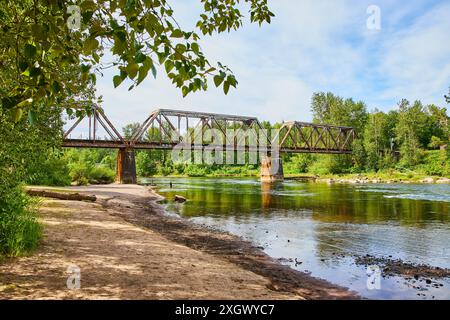 Rosty Truss Bridge über den Calm River mit Blick auf Reflexion Eye Level Stockfoto