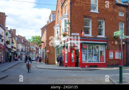 Ein Radfahrer radelt das Bailgate entlang der Post, und die Leute schauen durch das Fenster. Am späten Nachmittag. Lincoln, Lincolnshire, Vereinigtes Königreich. Stockfoto