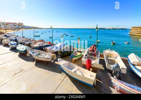 Fischerboote entlang des Hafens und im Meer am Strand La Caleta im historischen Zentrum der andalusischen Stadt Cádiz, Spanien. Stockfoto