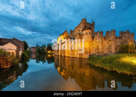 Abendlicher Blick auf ein beleuchtetes Schloss Gravensteen entlang der Leie in der historischen Altstadt von Gent, Belgien. Stockfoto