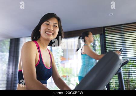 Porträt glücklicher asiatischer Freundinnen, die Sportkleidung tragen und zu Hause trainieren. Fitness, Bewegung, häusliches Leben, Freundschaft, Aktivität und Leben Stockfoto