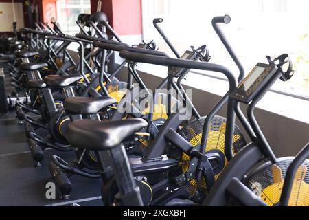 Reihe von Heimtrainer in einem Fitnessstudio, bereit für ein Training. Fitnessbegeisterte nutzen diese Geräte für Kardio- und Ausdauertraining. Stockfoto