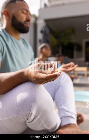 Junger birassischer Mann meditiert draußen, mit Kopierraum. Gelassenheit fließt, während er Yoga in einem ruhigen Garten praktiziert. Stockfoto