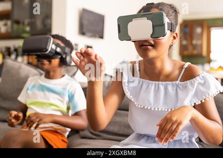 Bruder und Schwester im Teenageralter genießen VR-Spiele zu Hause. Sie tauchen in die virtuelle Realität ein und erleben gemeinsam modernste Technologien. Stockfoto