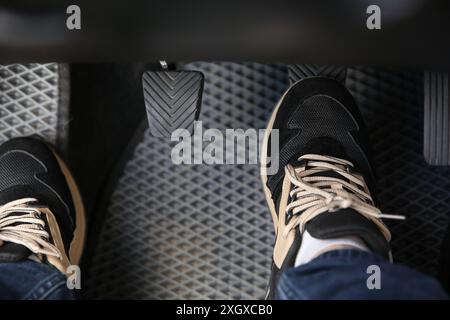 Mann in Turnschuhen drückt auf das Pedal der Autobremse, Nahaufnahme Stockfoto