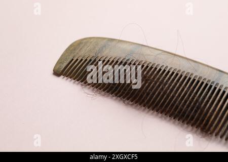 Kamm mit verlorenem Haar auf hellrosa Hintergrund. Alopezie-Problem Stockfoto