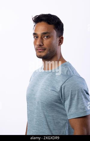Junger birassischer Mann posiert selbstbewusst in einem lässigen Hemd auf weißem Hintergrund. Sein entspanntes Auftreten und sein stylischer Look sind perfekt für einen modernen Lebensstil Stockfoto
