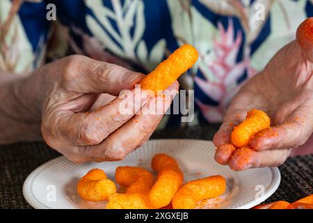 Senior-Mann, der Cheetos knabbert und ein Chaos macht, 2024, USA Stockfoto