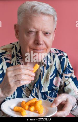 Senior-Mann, der Cheetos knabbert und ein Chaos macht, 2024, USA Stockfoto