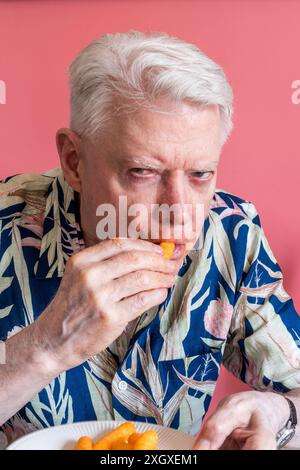 Senior-Mann, der Cheetos knabbert und ein Chaos macht, 2024, USA Stockfoto