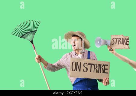 Protest gegen männlichen Landwirt, der ein Plakat mit STREIK- und Rechen-Text vor grünem Hintergrund hält Stockfoto