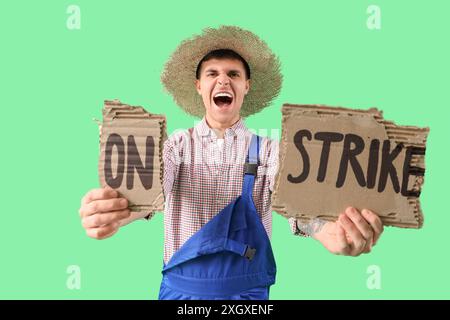 Protest gegen männlichen Landwirt, der ein Plakat mit STREIKTEXT vor grünem Hintergrund hält Stockfoto