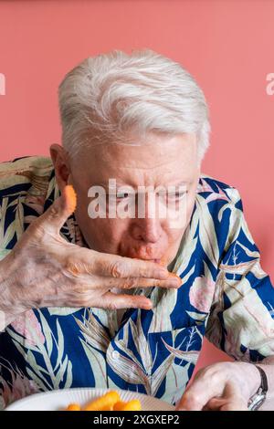 Senior-Mann, der Cheetos knabbert und ein Chaos macht, 2024, USA Stockfoto