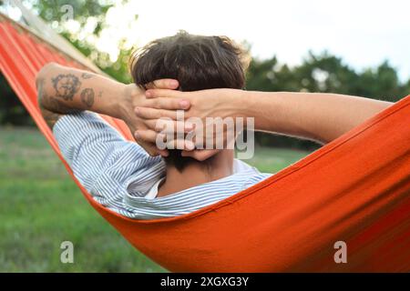 Junger Mann, der draußen in der Hängematte ruht Stockfoto