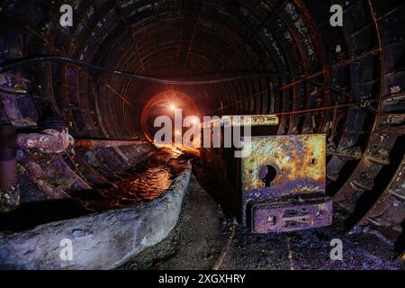 Alte, verlassene U-Bahn-Bautunnel mit rostiger Trolley-Lokomotive. Stockfoto