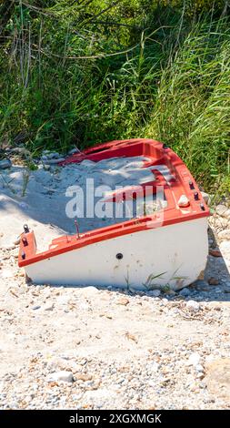 Ein altes verlassenes Boot an einem Sandstrand, der in Sand neben grünem Gras vergraben ist Stockfoto