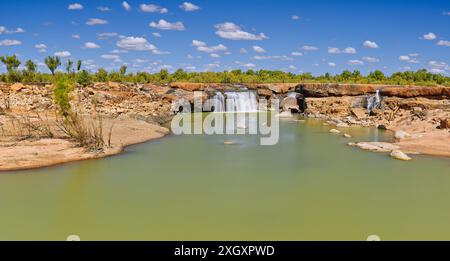 Panorama der Leichhardt Falls Tauchen Sie den Wasserfall über rote Felsen mit grünem Pool sonnigen Tag blauen Himmel, Golf von Carpentaria, Queensland, Australien Stockfoto