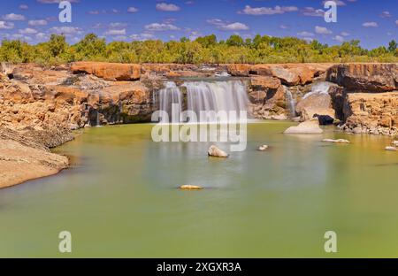 Panorama der Leichhardt Falls Tauchen Sie den Wasserfall über rote Felsen mit grünem Pool sonnigen Tag blauen Himmel, Golf von Carpentaria, Queensland, Australien Stockfoto