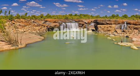 Panorama der Leichhardt Falls Tauchen Sie den Wasserfall über rote Felsen mit grünem Pool sonnigen Tag blauen Himmel, Golf von Carpentaria, Queensland, Australien Stockfoto