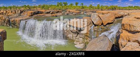 Panorama der Leichhardt Falls Tauchen Sie den Wasserfall über rote Felsen mit grünem Pool sonnigen Tag blauen Himmel, Golf von Carpentaria, Queensland, Australien Stockfoto