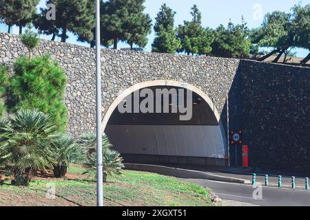 Tunnel mit einem Schild darauf, der in die Autobahn führt. Der Tunnel ist von Bäumen und einer Straße umgeben Stockfoto