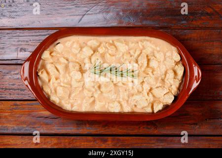 Hausgemachtes Hühnerstroganoff in Keramikschale auf rustikalem Holztisch. Draufsicht Stockfoto