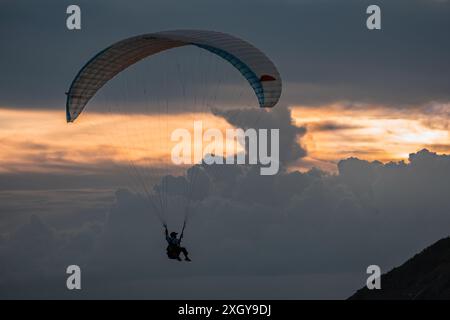 Gleitschirmfliegen in Phuket bei Sonnenuntergang. Die Leute genießen das Parasailing am Strand während des Sonnenuntergangs. Touristen, die über das Meer fliegen. Sportaktivitäten - Parasai Stockfoto