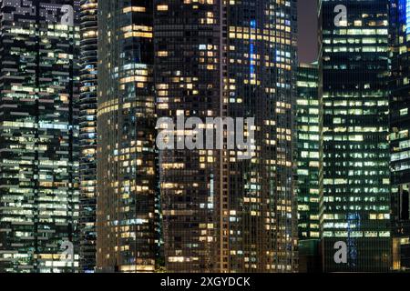 Erstaunlich leuchtende Fenster von Wolkenkratzern am Abend. Blick auf moderne Bürohochhäuser in Singapur. Malerische nächtliche Stadtlandschaft. Stockfoto