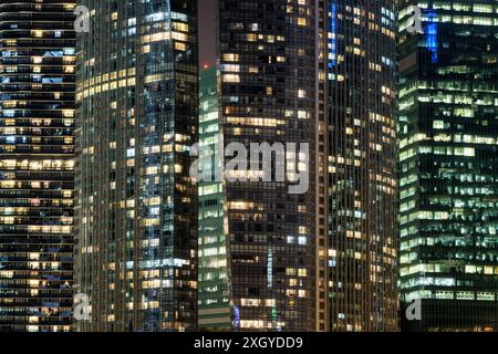 Erstaunlich leuchtende Fenster von Wolkenkratzern am Abend. Blick auf moderne Bürohochhäuser in Singapur. Malerische nächtliche Stadtlandschaft. Stockfoto
