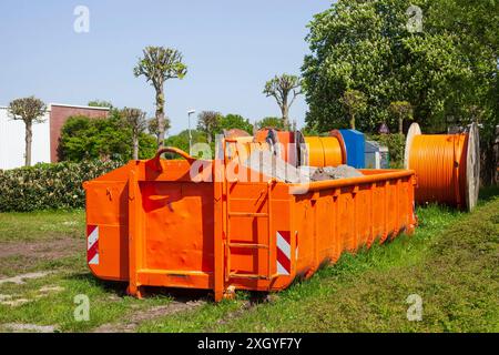 Container, orangefarbener Sprung für Bauschutt, der auf einer Wiese steht, Deutschland Stockfoto