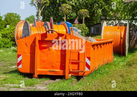 Container, orangefarbener Sprung für Bauschutt, der auf einer Wiese steht, Deutschland Stockfoto