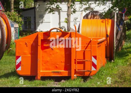 Container, orangefarbener Sprung für Bauschutt, der auf einer Wiese steht, Deutschland Stockfoto