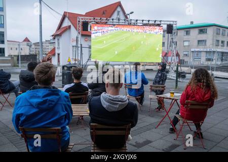 Nur wenige Fußballfans verfolgen bei regnerischem Wetter anlässlich der Fußball-Europameisterschaft UEFA EURO 2024 das Halbfinalspiel England gegen die Niederlande auf einer Leinwand auf dem Platz Hlemmur in Rsykajvik. / Nur wenige Fußballfans sehen das Halbfinalspiel zwischen England und den Niederlanden auf einem Bildschirm am Hlemmur-Platz in Rsykajvik bei regnerischem Wetter während der UEFA EURO 2024-Europameisterschaft. UEFA Fußball-Europameisterschaft - Fußballfans *** nur wenige Fußballfans sehen das Halbfinalspiel zwischen England und den Niederlanden auf einem Bildschirm bei Hlemmur S Stockfoto