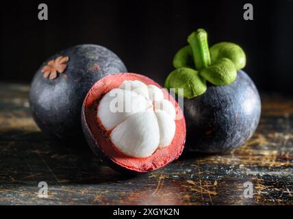 Nahansicht reifer Mangostan auf einem alten Holztisch. Tropische Früchte mit süßem weißem Fleisch. Gesunde Öko-Lebensmittel. Erzeugnis des ökologischen Landbaus. Stockfoto