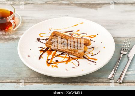 Heiße Churros mit Schokoladensauce auf Holztisch. Stockfoto