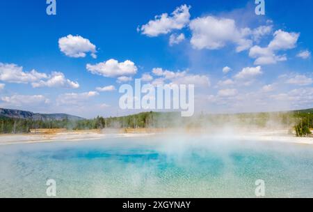 Leichte Dampfwolken steigen aus dem türkisfarbenen Zentrum des Sunset Lake unter einem tiefblauen Himmel im Black Sand Basin, Yellowstone-Nationalpark, Wyoming. Stockfoto