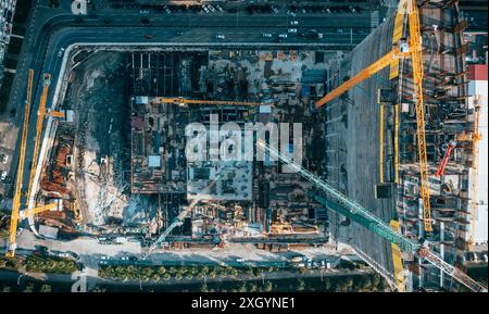 Blick von oben auf eine große Baustelle mit mehreren Kränen, umgeben von Straßen und Gebäuden in geschäftiger Stadtgegend. Stockfoto