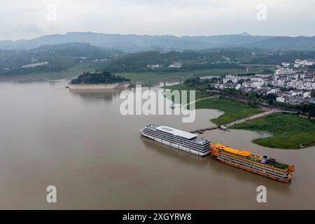 Chongqing. Juli 2024. Ein Drohnenfoto vom 10. Juli 2024 zeigt Kreuzfahrtschiffe, die in Shibaozhai anlegen, einem malerischen Ort im Zhongxian County im Südwesten Chinas in Chongqing. Shibaozhai sieht aus wie ein herzförmiger Bonsai, der mitten im Abschnitt der drei Schluchten von Yangtse Rier sitzt. Hier befindet sich eine 12-stöckige, 56 Meter hohe Holzpagode, die auf 20 Säulen steht und sich gegen die Klippe neigt. Dieses Gebäude stammt aus der Ming-Dynastie (1368–1644) und ist eine der wichtigsten Touristenattraktionen von Shibaozhai. Quelle: Liu Chan/Xinhua/Alamy Live News Stockfoto